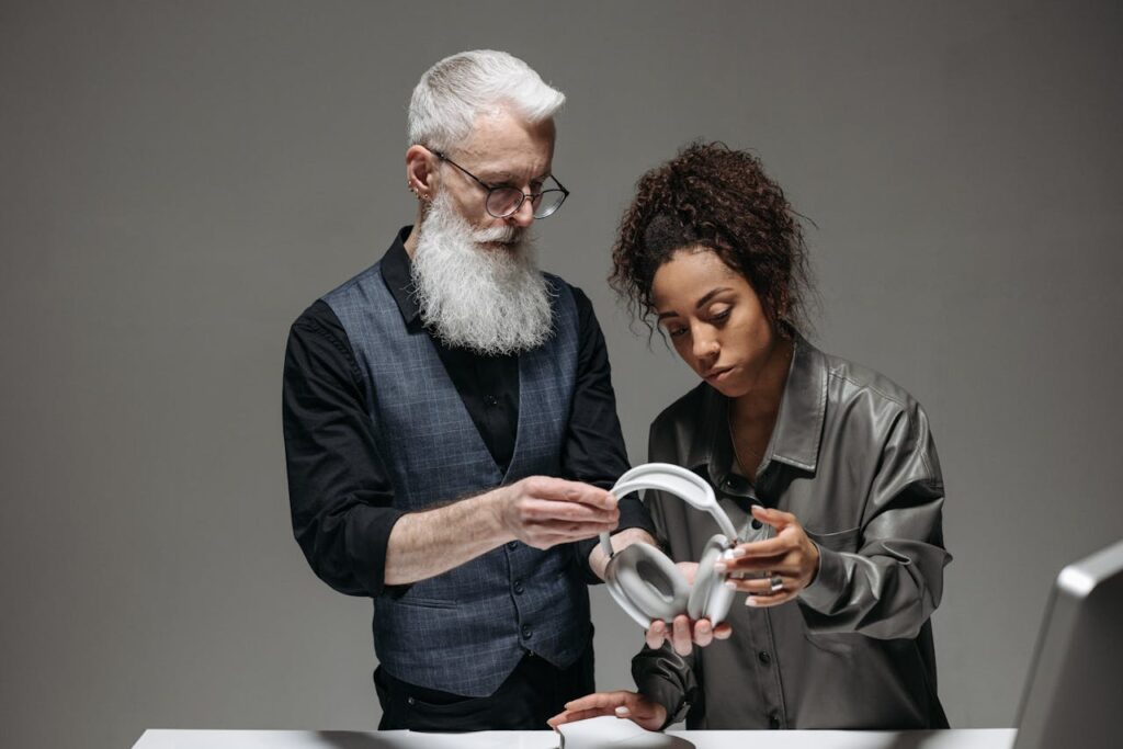 Senior caucasian man and black woman discussing headphones in an office setup.